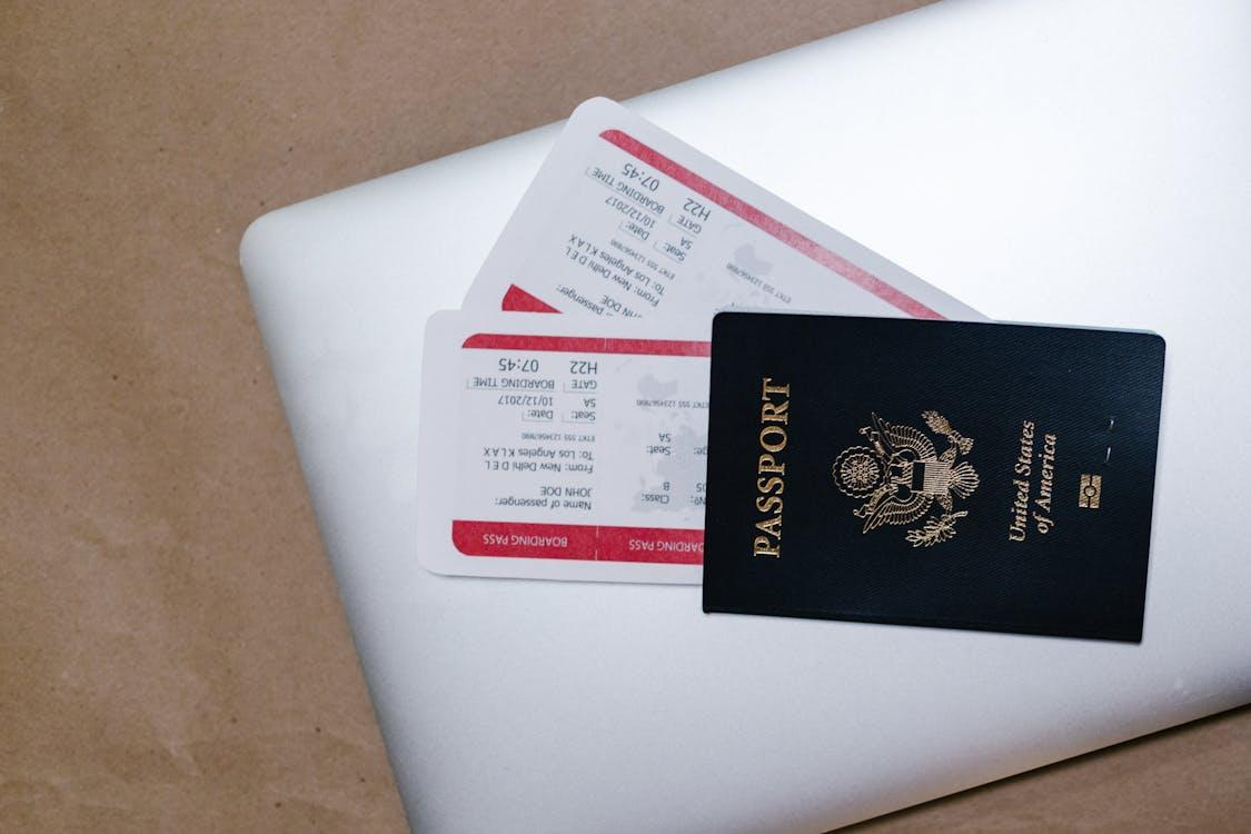 A close-up shot of a passport, tickets, and a laptop, showcasing travel preparations for an international trip.