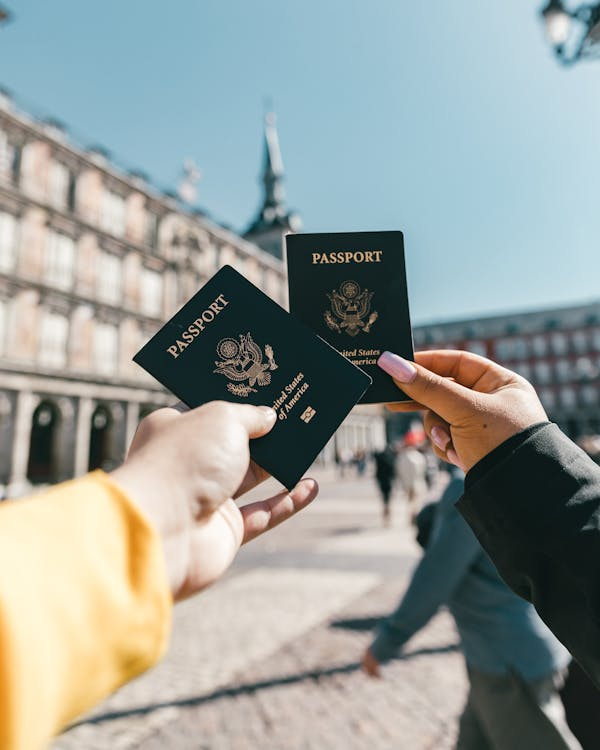A group of tourists holding US passports outdoors on a sunny day, representing the privilege of holding a US passport as part of dual citizenship