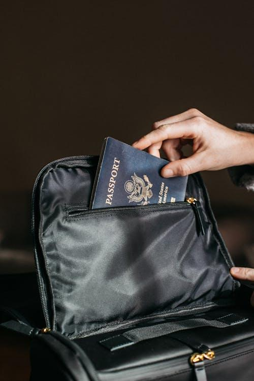A person placing a passport on a bag, highlighting the importance of securing travel essentials.