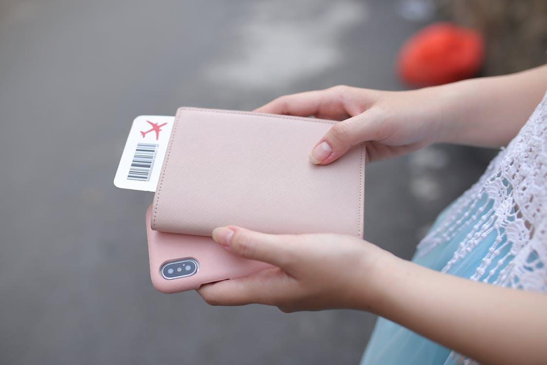 A person holding a pink smartphone and a wallet, emphasizing the importance of keeping your valuables safe while traveling